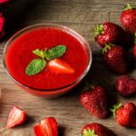 Salsa di fragole in una ciotola con fragole fresche e menta decorativa