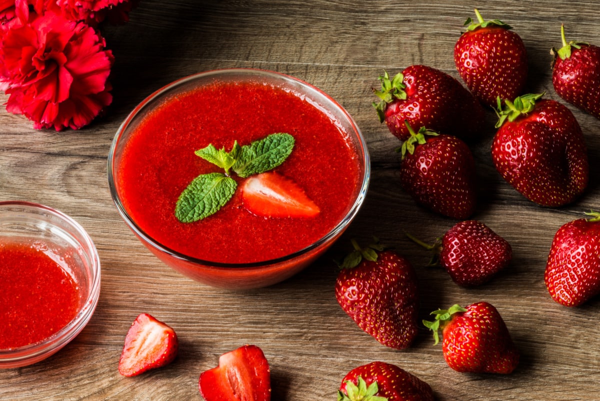 Salsa di fragole in una ciotola con fragole fresche e menta decorativa