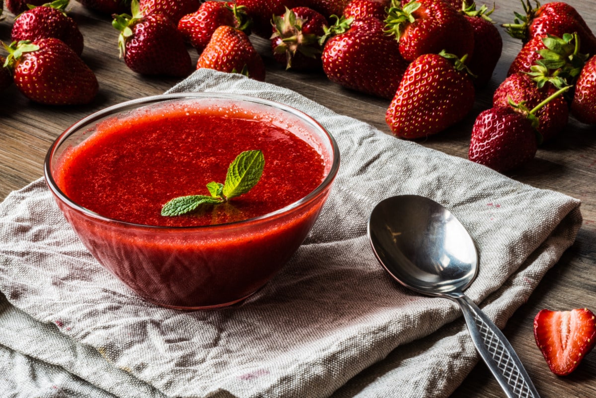 Salsa di fragole in una ciotola con cucchiaio e fragole fresche
